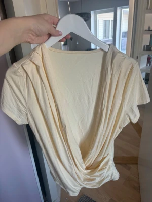 Ljusgul omlottopp med v-ringning ! 👡 - Trendig ljusgul omlottopp med djup v-ringning och korta ärmar. Toppen har en snygg draperad framsida och är gjord i mjukt bomullsmaterial. Perfekt för dig som vill ha en enkel men ändå stilren topp till garderoben. Passar L/M