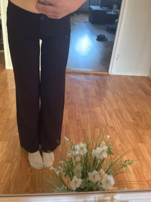 Svarta vida kostymbyxor - Säljer ett par svarta kostymbyxor med rak och vid passform. Byxorna har låg midja och klassisk design utan synliga detaljer eller fickor framtill. Perfekta för en stilren och enkel look.