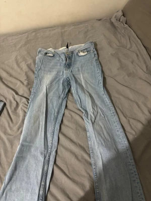 Ljusblå raka jeans från H&M - Säljer ett par ljusblå jeans från H&M med raka ben och klassisk femficksmodell. Jeansen har normal midja och är tillverkade i mjuk denim med lite stretch för extra komfort. Perfekta för en avslappnad och trendig look.