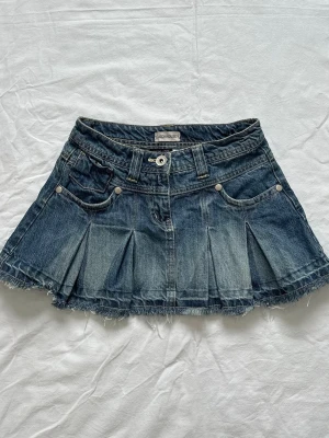 Jeanskjol - Blå kort jeanskjol från Clockhouse med fransig kant och veckade detaljer. Vid köp av flera varor får du rabatt 💛