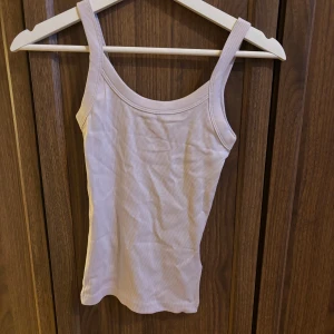  linnetopp från ginatricot - Säljer ett rosa/lila, ribbat linne från Gina tricot. Perfekt att styla till jeans eller kjol för en enkel och fräsch look. Materialet är mjukt och stretchigt för skön passform. Aldrig använd