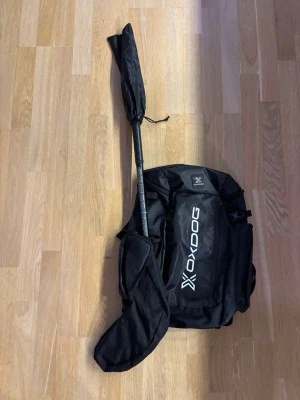 Svart Oxdog Innebandyryggsäck  - Ryggsäck från Oxdog med tillhörande klubbfodral för innebandyklubba. Toppskick, endast använd ett par gånger.