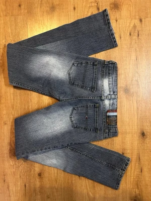 Blåa Tommy Hilfiger jeans - Blåa lågmidjade jeans från Tommy Hilfiger, säljes då de blivit för små! I en väldigt rak och inte så vid modell💕   🌸jag är 163 cm lång 🌸brukar ha storlek xs/s 🌸innerbenslängd: 82 cm   
