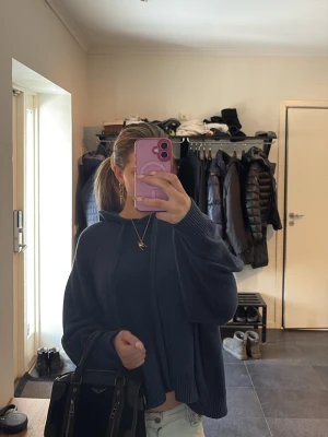 Mörkblå stickad hoodie - Mysig mörkblå stickad hoodie med huva och dragsko. Tröjan har en avslappnad passform, ribbade muddar och är lite croppad i modellen. Perfekt för dig som gillar en chill och enkel stil. Materialet känns mjukt och skönt mot huden.