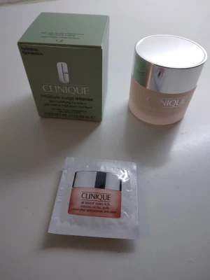 HELT NY OANVÄND Clinique Moisture Surge Intense 50ml - HELT NY Clinique Moisture Surge Intense hudkräm, 50 ml. Är en populär klassisk oljefri gel-creme som återfuktar och stärker hudens fuktbarriär. Passar mycket torr till kombinerad hud och innehåller aloe vera. Produkten är parfymfri och kommer i en ljusgrön kartong med gratisprov av matchande ögonkräm som ingår i köpet. Har stått en tid sedan inköpet men är helt oanvänd. Se bilder för egen bedömning. Nypris I butik för 50 ml: 449 kr.