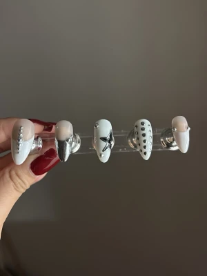 Press-on naglar med silverdetaljer - Snygga press-on naglar i mandelform med vit och nude bas, dekorerade med silverfärgade stenar, pärlor och 3D-metallik detaljer. Perfekt för dig som vill ha en trendig och unik nagelstil. Materialet är plast med glansig finish. 10st naglar!!!!