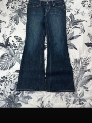 Mörkblå bootcut jeans - Säljer ett par mörkblå bootcut jeans med klassisk femficksdesign och kontrastsömmar. Jeansen har hög midja och breda ben som ger en retrovibe. Lågmidjade o passar mig som är 170