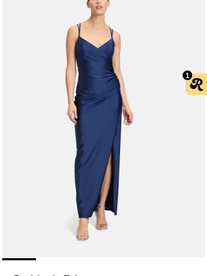 Marinblå balklänning Suddenly Princess - Snygg marinblå långklänning från Suddenly Princess med smala axelband och v-ringad front. Klänningen har en slits på sidan och öppen rygg med korsade band. Endast testad, prislapp finns kvar.