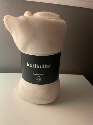 Vit fleecepläd från Kotikulta - Mysig vit fleecepläd från Kotikulta, perfekt att ha i soffan eller sängen. Pläden är mjuk och lätt, tillverkad i syntetmaterial och har en enkel, stilren design. Storlek 130x160 cm.