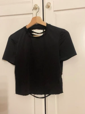 Svart crop top med cut-out rygg - Säljer en svart crop top med korta ärmar och rund hals. Toppen har en unik cut-out design i ryggen med flera horisontella slitsar jätte cool topp och passar till allt 