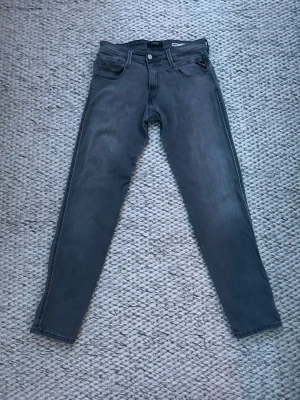 Gråa slim fit jeans från Replay - Gråa slim fit jeans från Replay .Jeansen har normal midja, raka ben och är tillverkade i denimtyg med stretch. Modell Anbass, powerstretch. Storlek W29 L30.