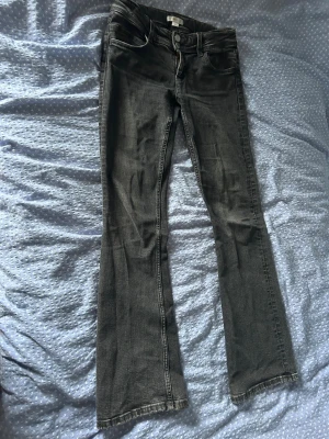 Grå bootcut jeans med låg midja - Säljer ett par grå bootcut jeans med låg midja och klassiska fem fickor. Storlek 164 men passar mig som brukar ha 34. Jeansen har en lätt utsvängd passform nedtill och detaljerade sömmar. Perfekta för dig som gillar en avslappnad men ändå snygg stil.