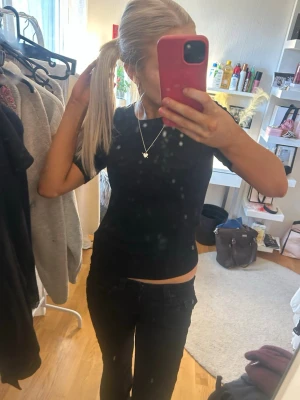 Svart croppad kortärmad topp - En enkel och stilren svart croppad topp med korta ärmar. Toppen har en tight passform och är perfekt att matcha med jeans eller kjol. Materialet känns mjukt och stretchigt, troligen bomull eller polyester. Snygg och basic för en trendig look.