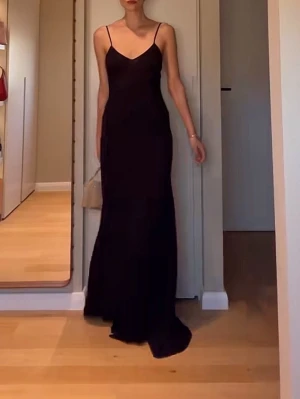 Victoria Beckham Svart viskos långklänning med smala axelband - Elegant svart långklänning med smala axelband och figurnära passform. Klänningen har en enkel och stilren design med v-ringad urringning och ärmlös siluett. Perfekt för dig som gillar minimalistisk och tidlös stil. Victoria Beckham xMango, XS