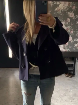 Mörkblå kappa - Stilren mörkblå kappa med bred krage och dubbelknäppning framtill. Jackan har två framfickor och är tillverkad i ett tjockare tyg som ger en klassisk look. Original pris 757kr💕