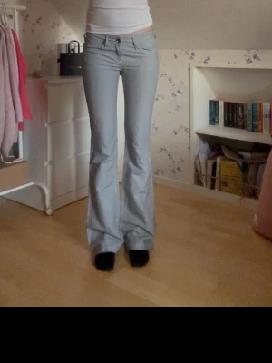 Ljusgrå Lågmidjade byxor  - Säljer ett par ljusgrå bootcut byxor med låg midja. Jeansen har vida ben. De är jeansliknande men inte riktigt jeansmaterial. Innerbenslängden är ca 90cm och midjemåttet rakt över 37. Smala i låren och inte så stretchiga💕💕💕