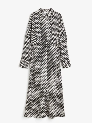 Svartvit mönstrad skjortklänning - Säljer en svartvit långklänning från H&M med grafiskt rutigt mönster. Klänningen har lång ärm, krage och knappar framtill. Skön passform och tillverkad i mjuk polyester som faller snyggt. Perfekt för dig som gillar statement-plagg!