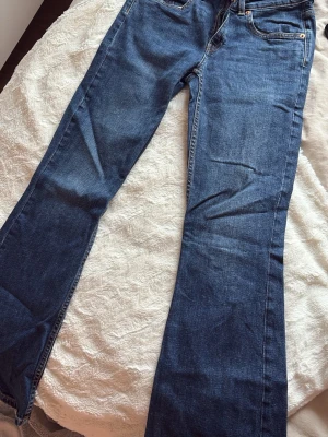Blå bootcut jeans från lager 157 - Säljer ett par klassiska blå bootcut jeans från lager 157 med femficksdesign och kontrastsömmar. Jeansen har en normal midja och är tillverkade i denim med en snygg tvätt. Perfekt för dig som gillar en tidlös och avslappnad look.