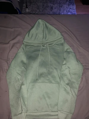 Ljusgrön hoodie med huva - Snygg ljusgrön hoodie med stor huva och dragsnören. Klassisk känguruficka framtill och ribbade muddar vid ärmslut och nederkant. Perfekt för en avslappnad och trendig stil. Materialet känns mjukt och bekvämt mot huden.