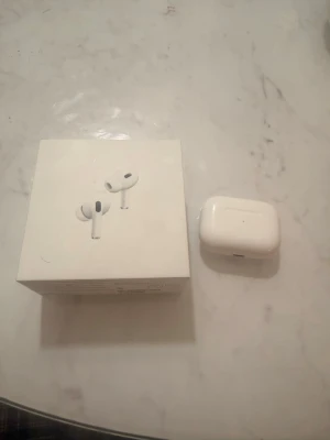 Apple AirPods Pro 2nd gen USB-C - Säljer ett par Apple AirPods Pro (2nd generation) med USB-C laddningsetui. Hörlurarna är vita och har en stilren, kompakt design i plast. Perfekta för dig som vill ha brusreducering och grymt ljud till mobilen eller datorn. Ladd kablarna till de är oanvända alltså dem är nya och Airpodsen är original! Vi erbjuder 1 gratis skal till Airpodsen.