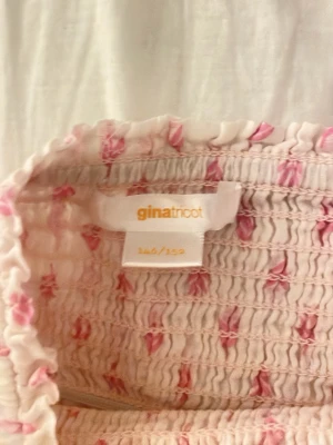 Vit och rosa kjol från Gina Tricot - Långkjol från Gina Tricot i vitt med rosa blommigt mönster och fina spetsdetaljer. Kjolen är gjort av luftigt bomullstyg, perfekt för varma dagar.