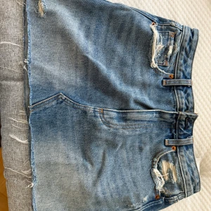 Blå jeanskjol med slitningar - Säljer en blå jeanskjol med råa kanter och slitna detaljer framtill och baktill🩵💙