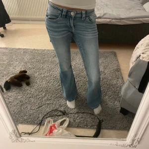 Bootcut jeans från Gina Tricot - Snygga ljusblå bootcut jeans från Gina Tricot i storlek S 14+. Jeansen har klassisk femficksdesign, låg midja och är tillverkade i mjukt denimtyg. Passformen är loose upptill och utsvängda ben ger en cool siluett.