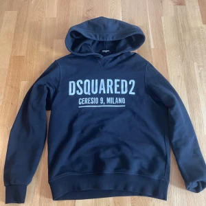 Svart hoodie från Dsquared2 - Svart hoodie från Dsquared2 med stor vit logga och texten 'Ceresio 9, Milano' på bröstet. Klassisk modell med huva och långa ärmar. Mjuk insida och ribbade muddar. (Äkta) mycket bra skick