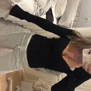 Svart ribbad långärmad topp - Säljer en svart ribbad topp med lång ärm och snygg v-ringad urringning. Toppen är figurnära och har en stretchig passform.