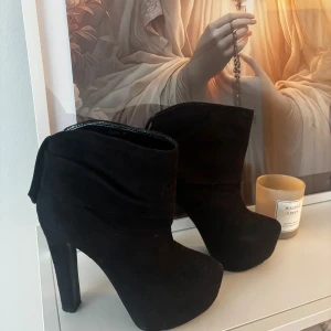 Svarta stövletter med hög klack - Snygga svarta stövletter från Sandro med hög klack och plattform. Skorna är i mocka och har en stilren, rund tå. Perfekta för dig som vill ha en edgy och trendig look. Använda max 5 gånger