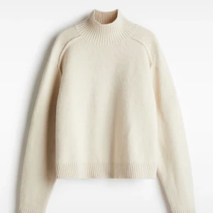 Beige polotröja med ribbad krage - Snygg beige polotröja med ribbad hög krage och muddar vid ärmslut och nederkant. Tröjan har en clean look och är stickad i mjukt material, perfekt för lager-på-lager. Passformen är normal och ärmarna är långa. Enkel att styla med jeans eller kjol.