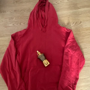 Röd hoodie med huva i bomull - Röd hoodie med klassisk huva och känguruficka framtill. Tillverkad i mjuk bomull, perfekt för chill dagar. Långärmad modell med ribbade muddar och avslappnad passform.