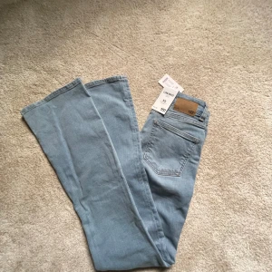 Bootcut jeans ljusblå från 157 XS - Ljusblå bootcut jeans från 157 i storlek XS. Modellen är lågmidjad med klassisk femficksdesign och full längd. Jeansen är tillverkade i mjukt denimtyg och har en snygg, utsvängd passform nertill. Perfekta för dig som gillar retrovibbar och stilren look.