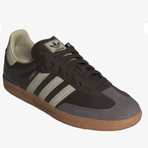 Adidas Samba sneakers brun/grå 40⅔ - Adidas Samba sneakers i brunt och grått med klassiska vita ränder på sidorna. Ovandel i skinn och mocka, gummisula i ljusbrun färg. Ikonisk retrostil med snörning och rund tå. Perfekta för dig som gillar streetwear och tidlös design.