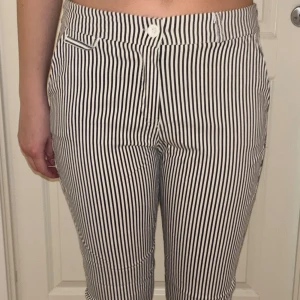 Randiga byxor i svartvitt, storlek XL - byxor med svartvita vertikala ränder och klassisk passform. Byxorna har fickor fram och bak. 