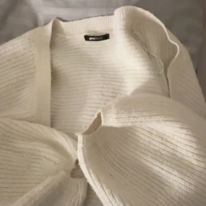 Vit stickad kofta från Gina Tricot - Mysig vit stickad kofta från Gina Tricot i storlek S. Koftan har en öppen front, ribbad struktur och långa ärmar med en relaxed fit. Perfekt att slänga över ett linne eller t-shirt för en chill och stilren look.