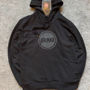 Colmar Hoodie, HELT NY! Strl M - Svart hoodie från Colmar                                            Storlek:M                                                                         Skick: 10/10 (HELT NY MED TAGS).                           Nypris på 1800.       Passar S bättre            Jag på sista bilden är 180