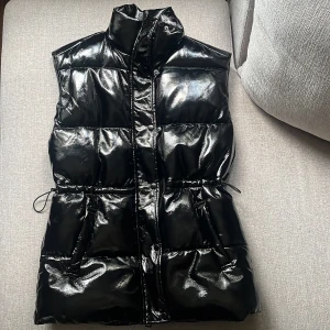 Svart väst - Svart väst med lackimmitatio, knappt använd så i nyskick. Går att dra åt i midjan 