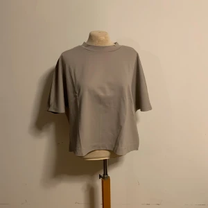 Beige topp från Visual Clothing Project - Säljer en beige topp från Visual Clothing Project i storlek M. Toppen har en loose passform, korta ärmar och rund halsringning. Tillverkad i mjukt material som känns skönt mot huden. Enkel och stilren design som passar till många olika outfits.