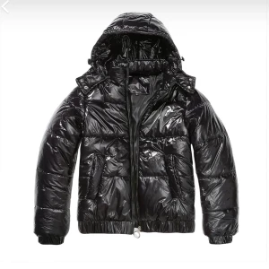 Svart glansig pufferjacka med huva - Säljer en svart pufferjacka med glansig finish och huva. Jackan har quiltad design, dragkedja framtill och elastiska muddar vid ärmslut och nederkant. Perfekt för dig som vill ha en cool och varm jacka med streetkänsla.