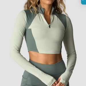 Cropped tränings-tröja ICIW M - NY - Sportig croppad långärmad tröja från ICIW i två nyanser av grönt. Tröjan har half zip, hög krage och ventilerande mesh-detaljer. Perfekt för träning och har en tight passform som framhäver midjan. Ny med prislapp! Ord pris 599kr