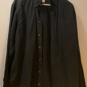 Eton linneskjorta slim fit svart - Svart linneskjorta från Eton, slim fit, ficka på bröstet, har vissa tecken på användning men inga defekter, passar herrstorlek L, originalpris 2000 kr. 