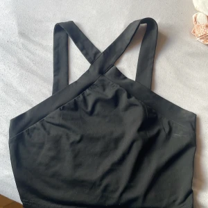 Svart topp från SHEIN - Svart-topp från SHEIN med breda axelband som korsas i ryggen. Toppens material är mjuk polyester med lite stretch för en bekväm passform. Snygg och stilren design som ger en cool vibe till din outfit.