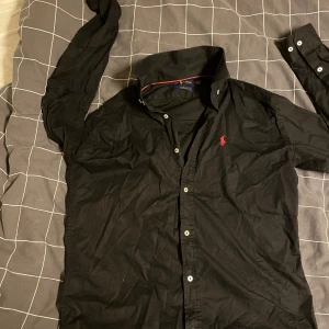 Svart skjorta från Ralph Lauren - Svart långärmad skjorta från Ralph Lauren i slim fit-modell. Storlek XL men passar även L  Priset går att diskutera 