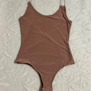 Ljusrosa bodysuit från Gina Tricot - Säljer en ljusrosa bodysuit från Gina Tricot med tunna axelband och djup rygg. Bodyn är i ett mjukt, stretchigt material och har en enkel, stilren design som passar perfekt till jeans eller kjol. Aldrig använd. Skriv om bilder önskas 🥰