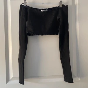 Svart ribbad offshoulder topp Chiquelle - Superfin och stilren croppad tröja som slutar precis under brösten, perfekt för en trendig look! Gjord i ett lyxigt tjockt material som känns exklusivt och sitter snyggt på kroppen. Tröjan har långa ärmar som går ut över händerna, en smickrande ribbade design och fina volanger för en extra elegant touch. Använd endast 1 gång och i nyskick! Säljer då den inte kommer till användning.  Vänligen läs min bio innan du gör ett köp; där hittar du bland annat information om leveransprocessen med mera 😊
