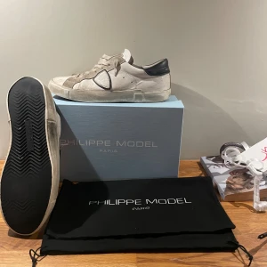 Philippe Model vita sneakers strl 42 - Snygga Philippe Model PRSX Low Man sneakers i vitt skinn med svarta detaljer på hälen och sidan. Klassisk låg modell med snörning och platt sula. Kommer med originalkartong och dustbag. Perfekta för dig som gillar stilrena och trendiga sneakers. Allt og medföljer! Hör av er om frågor och ifall ni vill ha fler bilder😃
