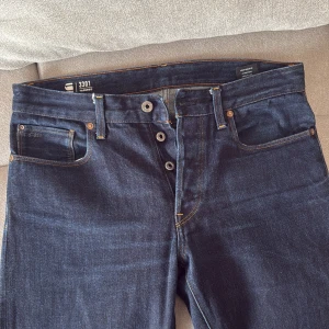 G-Star RAW 3301 mörkblå tapered jeans - Snygga mörkblå jeans från G-Star RAW, modell 3301 Tapered. Klassisk femficksdesign med kontrastsömmar och knappgylf. Pris kan diskuteras 