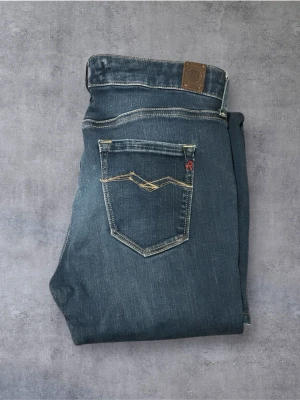 Replay Jeans - Snygga blå jeans från Replay med klassisk femficksdesign och kontrasterande gula sömmar. Jeansen har en rak passform och är tillverkade i slitstarkt denimtyg. Perfekta för en avslappnad och trendig look.