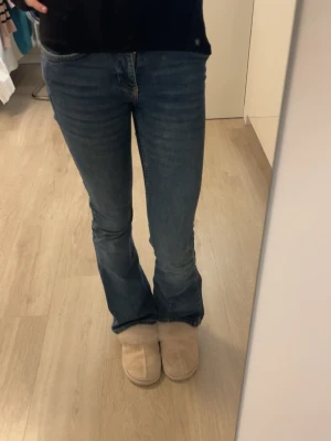 Blå bootcut jeans - Snygga blå bootcut jeans med klassisk femficksdesign och normal passform. Jeansen har en något utsvängd benslut och är tillverkade i slitstarkt denimtyg av bomull. Perfekta för en avslappnad och trendig look.